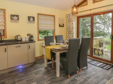 A kitchen dining area with a dining table four chairs kitchen cabinets and a sliding glass door at Nicky Nook Lodge in Scorton