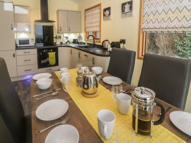 A kitchen with a dining table set with plates cups and a teapot at Nicky Nook Lodge in Scorton