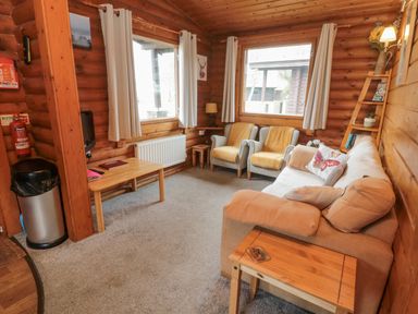 A wooden living room with a beige sofa two armchairs a coffee table and windows at Glanton in Longframlington