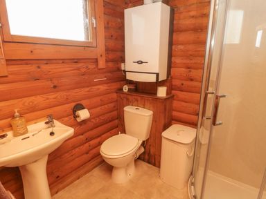 A bathroom with a sink, toilet, shower, window and wooden walls at Glanton in Longframlington