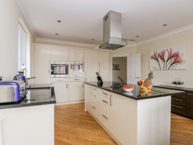 A kitchen with a central island with black countertop and built-in stove with fruit bowls on it at The Gansey Girl in Bridlington