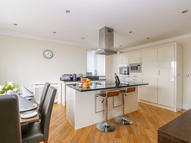 A kitchen with an island with two stools and a dining table with chairs at The Gansey Girl in Bridlington