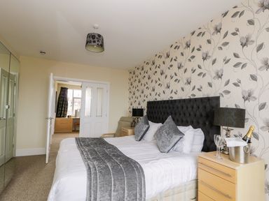 A bedroom with a bed a bedside table with a lamp and champagne at The Gansey Girl in Bridlington