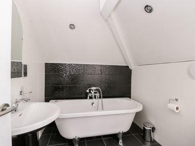 A bathroom with a freestanding bathtub a sink and a toilet paper holder at The Gansey Girl in Bridlington