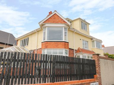 A two-story house with bay windows a black wooden fence and a brick wall at The Gansey Girl in Bridlington