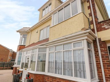 The front exterior of a multi-story house with tiled roof and windows with decorative glass at The Gansey Girl in Bridlington