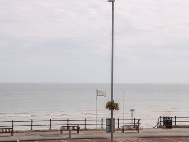 A seaside promenade with benches a flagpole a lamp post and the ocean in the background at The Gansey Girl in Bridlington