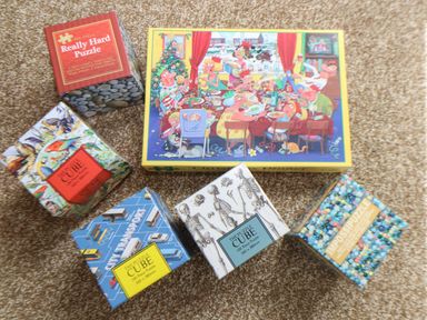 Six puzzle boxes on a carpet including really hard puzzle and puzzle cubes with various designs