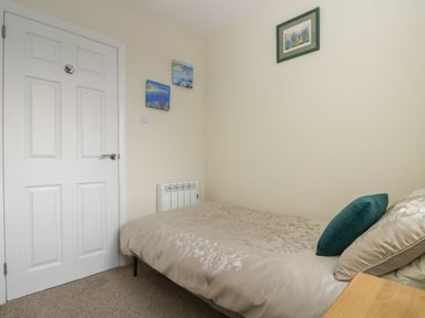 A bedroom with a single bed and decorative wall art at Tremethic in Trewoon