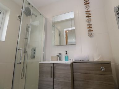 A bathroom with a shower and sink at Sandpiper in Perranporth