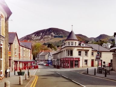 A street with buildings and parked cars near hills at Llys Madoc The Top Flat in Penmaenmawr