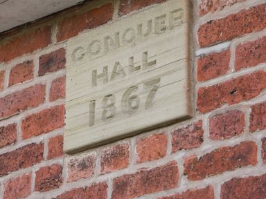 A brick wall with a stone plaque reading Conquer Hall 1867 at Conquer Hall in Hendomen near Montgomery