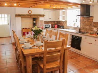 A kitchen with wooden dining table set with plates glasses and flowers at Conquer Hall Hendomen near Montgomery