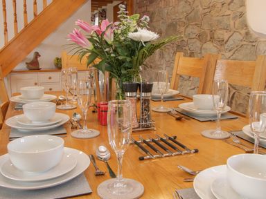 A dining table with white dinnerware glasses and a flower arrangement at Conquer Hall in Hendomen near Montgomery