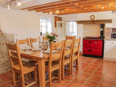 A dining area with a wooden table and chairs next to a red stove in a kitchen at Conquer Hall Hendomen near Montgomery