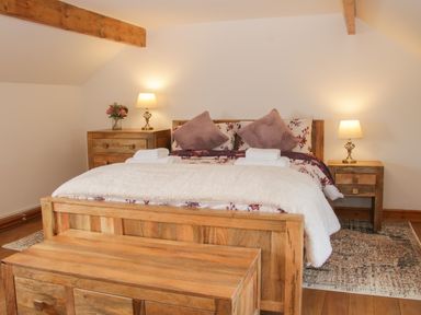 A bedroom with a wooden bed frame bedside tables lamps and towels on the bed at Conquer Hall in Hendomen near Montgomery