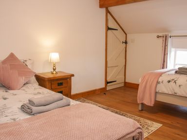 A bedroom with two beds wooden nightstand a lamp and a door at Conquer Hall in Hendomen near Montgomery