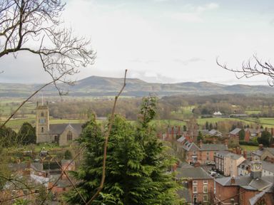 A town with a church and houses surrounded by trees and hills at Conquer Hall in Hendomen near Montgomery