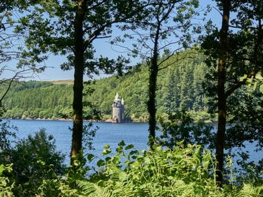 A lake with a small tower on the far shore surrounded by trees at Conquer Hall in Hendomen near Montgomery