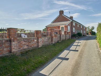 A brick house with a brick and iron fence along a narrow road at Conquer Hall in Hendomen near Montgomery