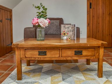 A wooden coffee table with a vase of flowers and a guest book in front of a brown armchair in a room at Conquer Hall Hendomen near Montgomery