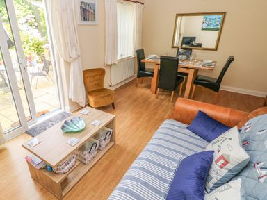 A living room with a sofa and coffee table next to a dining table with chairs at 2 Primrose Cottage Saundersfoot