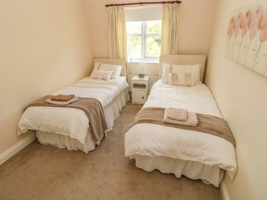 A bedroom with two single beds and a window in between at 2 Primrose Cottage in Saundersfoot