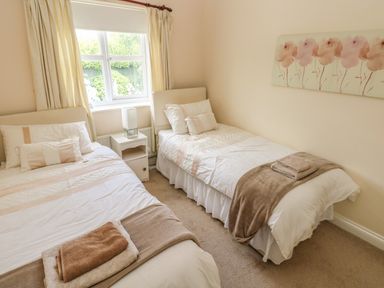 A bedroom with two single beds a nightstand and a window at 2 Primrose Cottage Saundersfoot