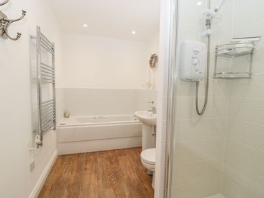 A bathroom with a bathtub sink toilet heated towel rail and shower at Waterside in Beadnell