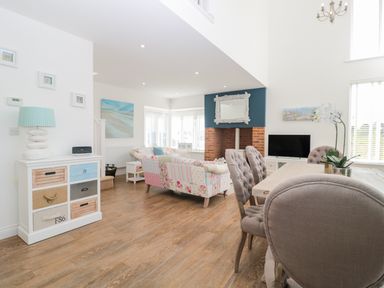 A living room with patchwork sofas a dining table with chairs and a fireplace at Waterside in Beadnell