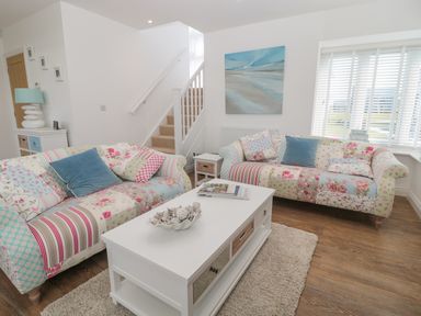 A living room with patterned sofas and a white coffee table at Waterside in Beadnell