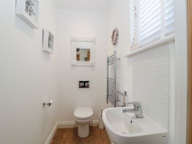 A small bathroom with a toilet a sink a mirror and a window with blinds at Waterside in Beadnell