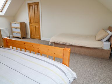 A bedroom with two single beds a wooden chest of drawers a wooden door and a skylight window at Croghan in Portsalon