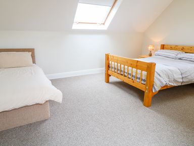A bedroom with two beds a wooden nightstand and a skylight window at Croghan in Portsalon