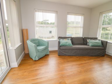 A sitting room with a gray sofa and a light green armchair on wood floor at Croghan in Portsalon