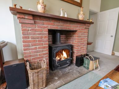 A living room with a fireplace and wood stove at 20A St Hilda's in Whitby