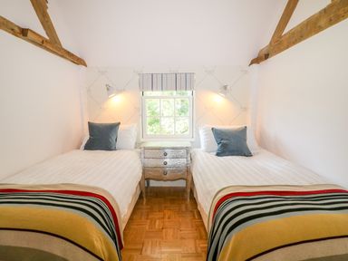 A bedroom with two single beds separated by a nightstand under a window at The Hemmel in Faringdon