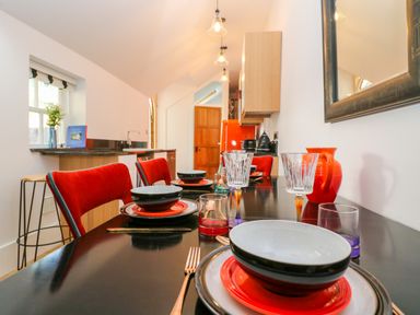 A dining table set with bowls and glasses next to red chairs in a kitchen at The Hemmel in Faringdon