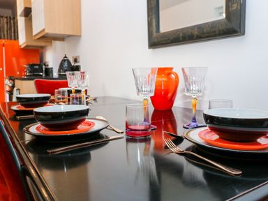 A dining table with plates bowls glasses cutlery and a red jug in a kitchen at The Hemmel in Faringdon