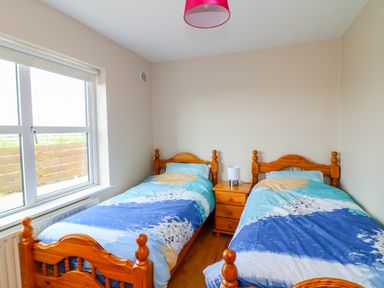 A bedroom with two wooden single beds separated by a wooden nightstand with a lamp at Doornogue in Churchtown near Fethard-on-Sea