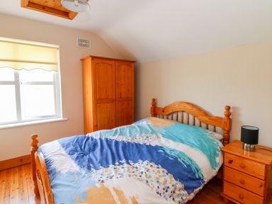 A bedroom with a wooden bed wardrobe and bedside table at Doornogue Churchtown near Fethard-on-Sea