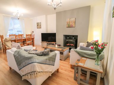 A living room with two white sofas a coffee table a television and a dining table with chairs at Yr Adfa The Retreat in Blaenau Ffestiniog