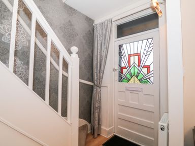 A staircase next to a front door with stained glass window and a curtain at Yr Adfa The Retreat in Blaenau Ffestiniog