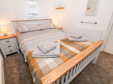 A bedroom with a bed with pillows and folded towels on a checkered blanket at Yr Adfa The Retreat in Blaenau Ffestiniog