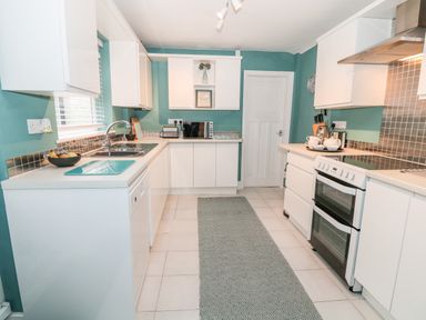 A kitchen with white cabinets a tiled floor a double oven a microwave and a sink at Yr Adfa The Retreat in Blaenau Ffestiniog