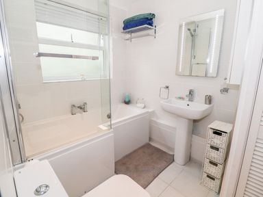 A bathroom with a bathtub a sink a mirror and storage baskets at Yr Adfa The Retreat in Blaenau Ffestiniog