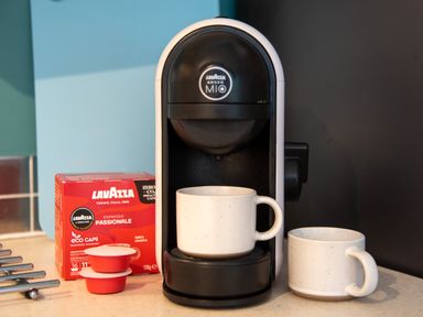 A coffee machine with two white mugs and a box of Lavazza coffee capsules on a kitchen counter at Yr Adfa The Retreat in Blaenau Ffestiniog