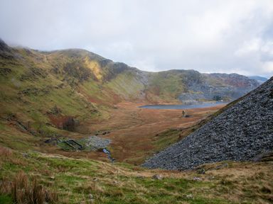 A valley with grassy hills a small stream and a lake in the distance at Yr Adfa The Retreat in Blaenau Ffestiniog
