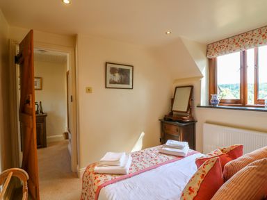 A bedroom with a bed folded towels a wooden dressing table and a window at Great Bradley Cottage in Withypool