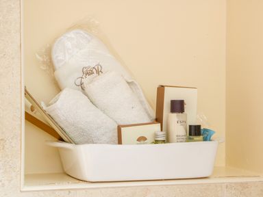 A bathroom shelf with white towels slippers and toiletries at Great Bradley Cottage in Withypool